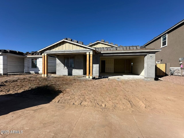 property in mid-construction with dirt driveway and board and batten siding