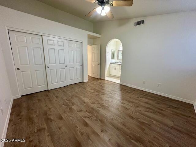 10101 N 91st Ave Unit 88, Peoria, AZ 85345 - unfurnished bedroom with arched walkways, dark wood-type flooring, a closet, a ceiling fan, and ensuite bath