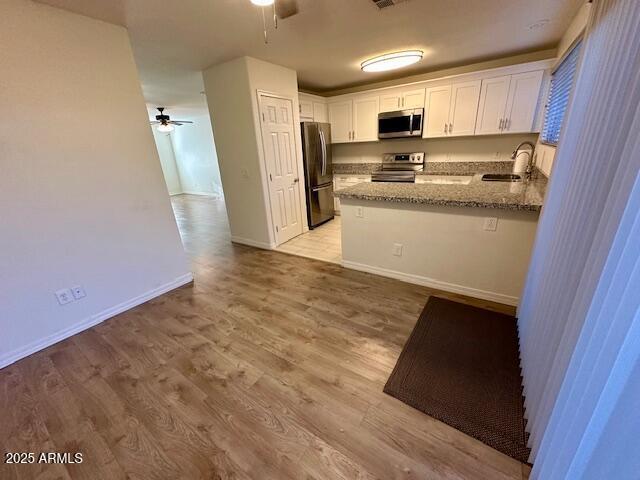 10101 N 91st Ave Unit 88, Peoria, AZ 85345 - kitchen featuring stainless steel appliances, a ceiling fan, white cabinetry, a peninsula, and stone counters