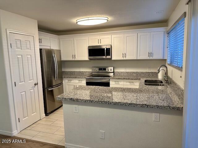 10101 N 91st Ave Unit 88, Peoria, AZ 85345 - kitchen featuring appliances with stainless steel finishes, a peninsula, white cabinetry, and stone counters
