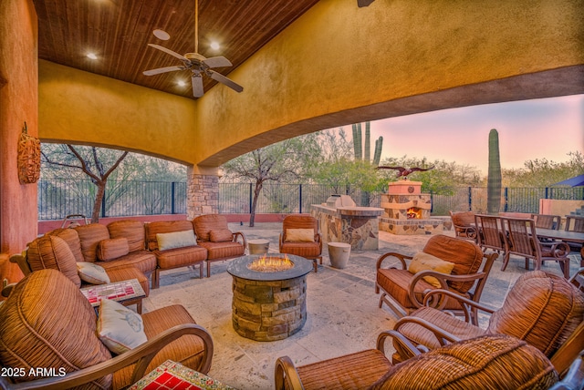 patio terrace at dusk with ceiling fan and an outdoor living space with a fireplace