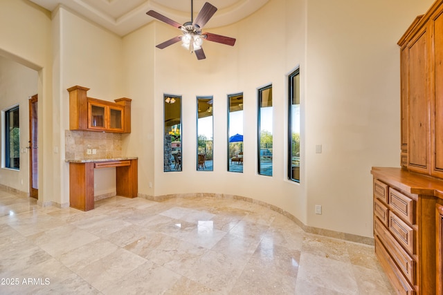 unfurnished living room featuring a towering ceiling and ceiling fan