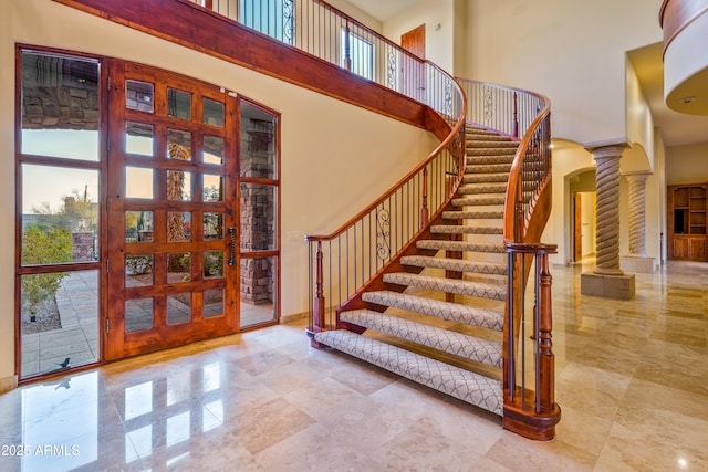 foyer with decorative columns, a high ceiling, and a wealth of natural light