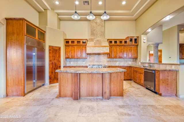 kitchen featuring a towering ceiling, decorative light fixtures, custom exhaust hood, kitchen peninsula, and stainless steel appliances