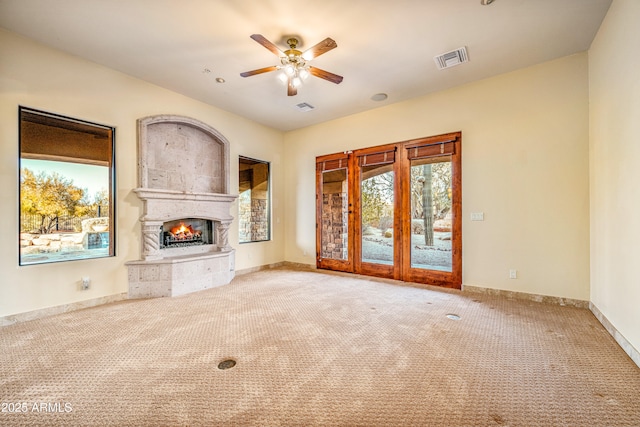 unfurnished living room with light carpet, a fireplace, and ceiling fan