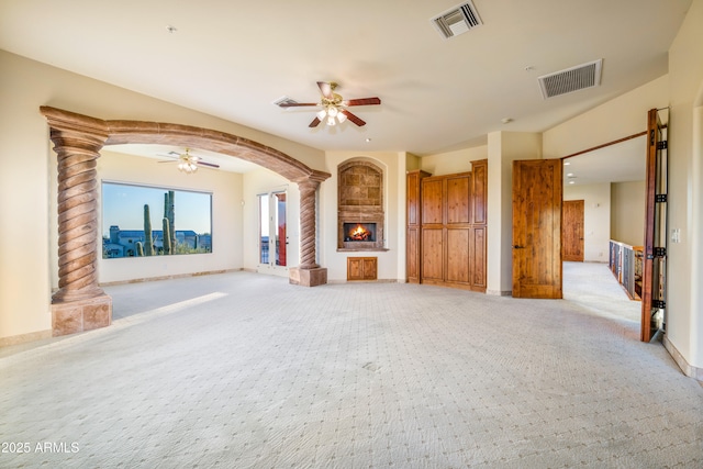 unfurnished living room with ornate columns, light colored carpet, and ceiling fan