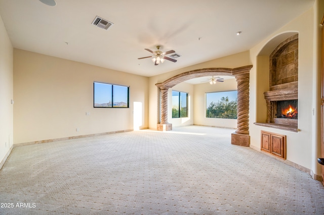 unfurnished living room featuring ornate columns, light carpet, and ceiling fan