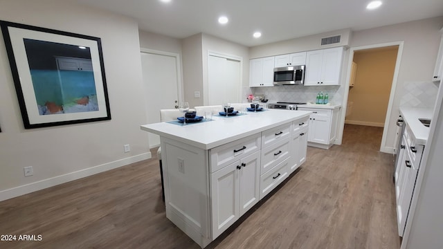 kitchen with a center island, white cabinetry, appliances with stainless steel finishes, and tasteful backsplash