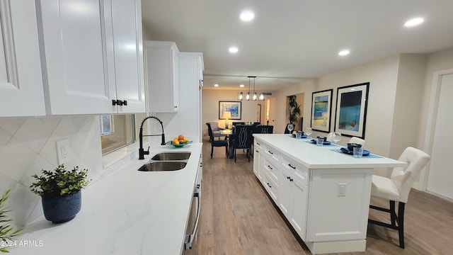 kitchen featuring white cabinetry, sink, a center island, a breakfast bar area, and light wood-type flooring