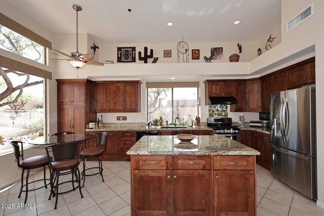 6966 E Bramble Berry Ln, Scottsdale, AZ 85266 - kitchen featuring stainless steel appliances, under cabinet range hood, a center island, light tile patterned flooring, and a sink