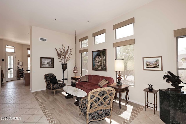 6966 E Bramble Berry Ln, Scottsdale, AZ 85266 - living room featuring light tile patterned floors, a towering ceiling, and baseboards
