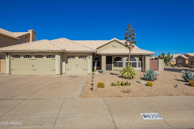 view of front of house with a tiled roof, an attached garage, driveway, and stucco siding