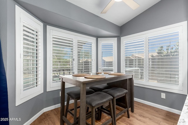 dining space with lofted ceiling, wood finished floors, a ceiling fan, and baseboards