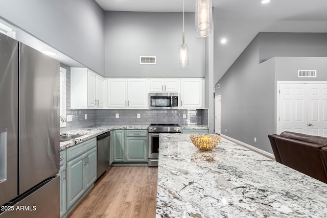 kitchen featuring appliances with stainless steel finishes, visible vents, a sink, and high vaulted ceiling