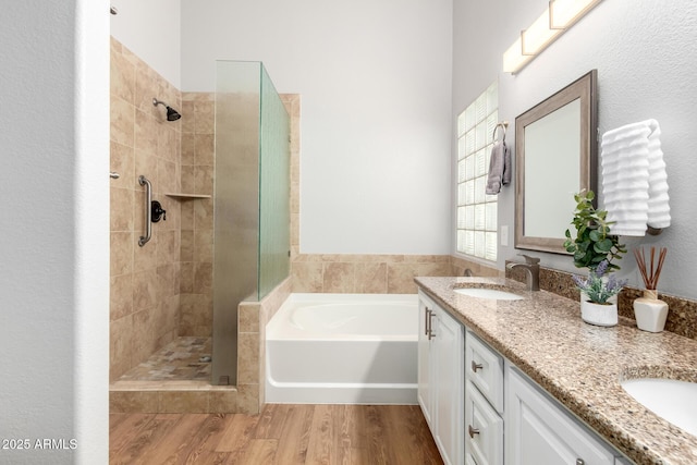 bathroom with a tile shower, double vanity, a sink, and a bath