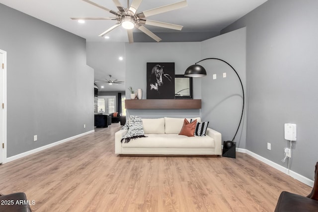 living area featuring wood finished floors, a ceiling fan, and baseboards