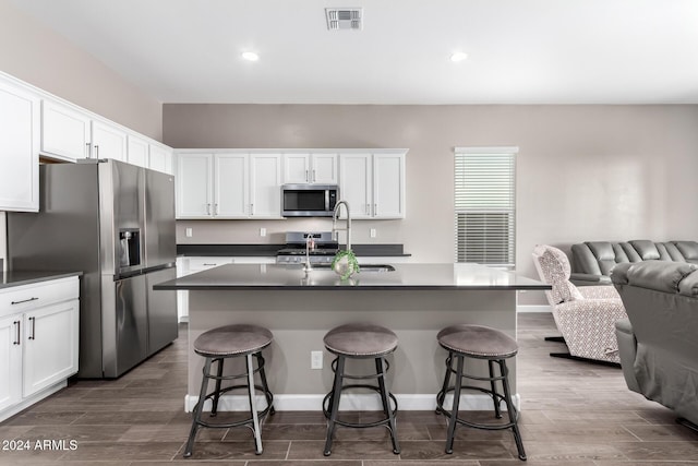 kitchen with white cabinetry, a center island with sink, and stainless steel appliances