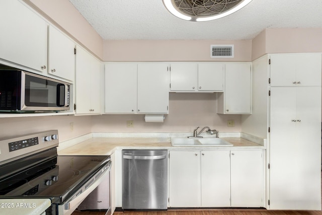 kitchen featuring visible vents, appliances with stainless steel finishes, light countertops, and a sink