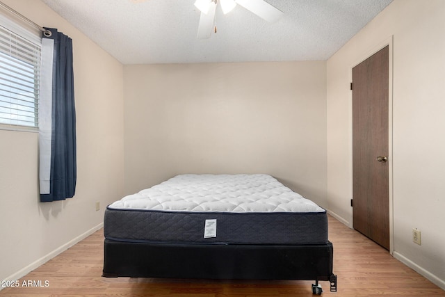 bedroom featuring light wood-style floors, a textured ceiling, and baseboards