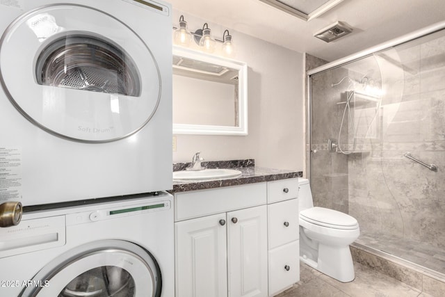 full bathroom featuring visible vents, toilet, vanity, stacked washing maching and dryer, and a shower stall