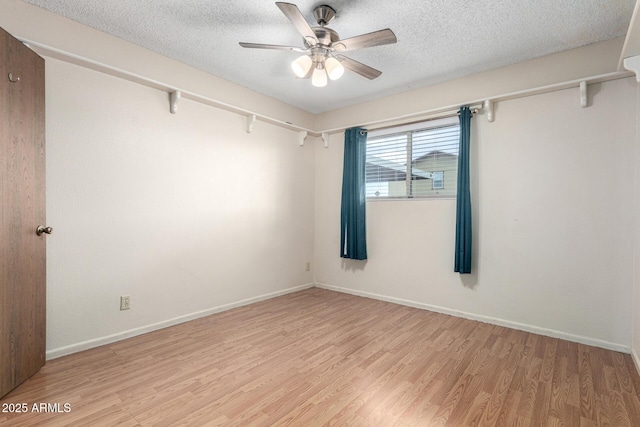 spare room with light wood-style floors, ceiling fan, baseboards, and a textured ceiling