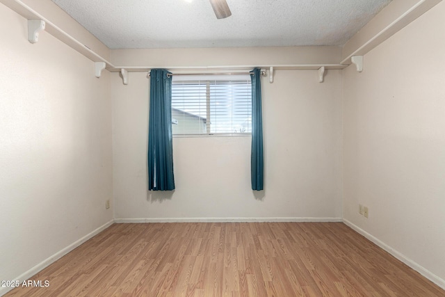 spare room with a textured ceiling, ceiling fan, light wood-type flooring, and baseboards