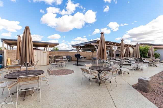 view of patio with outdoor dining space, fence, and a gazebo