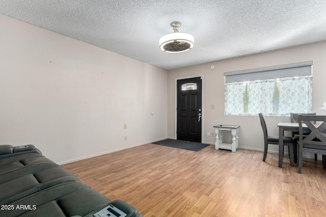 entrance foyer featuring a textured ceiling, light wood-style flooring, and baseboards