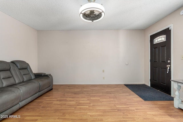 living area with light wood-style floors, baseboards, and a textured ceiling