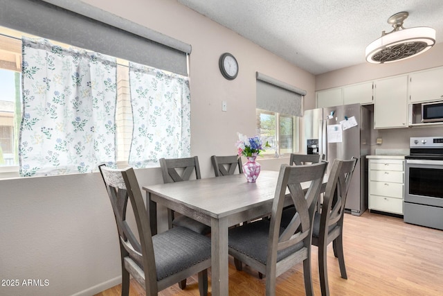 dining space featuring a textured ceiling and light wood-style flooring