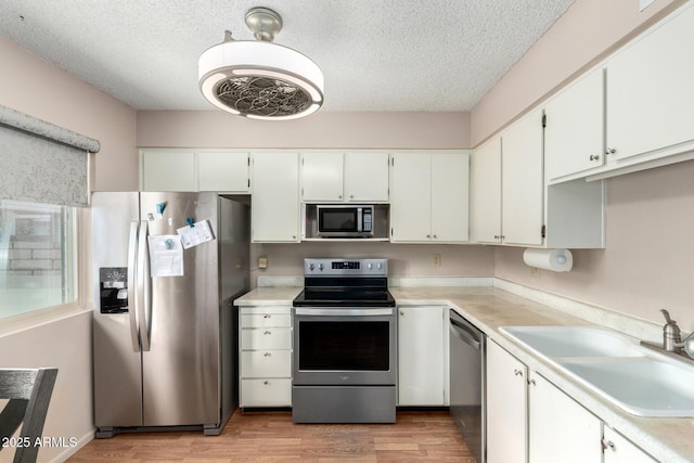 kitchen with appliances with stainless steel finishes, light countertops, white cabinetry, and a sink