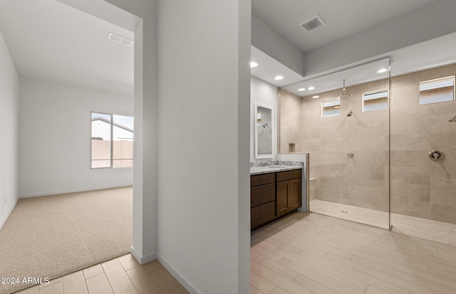 bathroom with tiled shower, wood-type flooring, and vanity