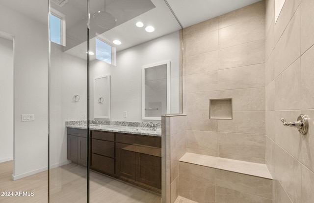 bathroom with a tile shower and vanity