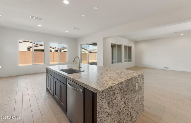 kitchen featuring a center island with sink, dishwasher, light wood-type flooring, and sink