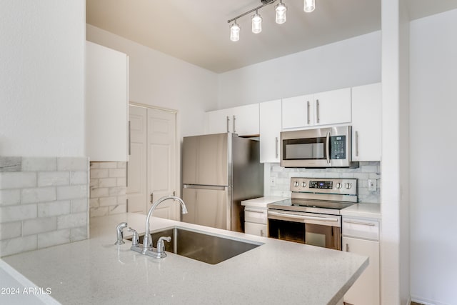 kitchen featuring kitchen peninsula, sink, tasteful backsplash, white cabinetry, and appliances with stainless steel finishes