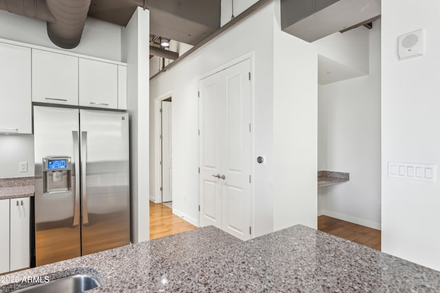 kitchen with white cabinetry, stainless steel fridge, light hardwood / wood-style flooring, and light stone countertops