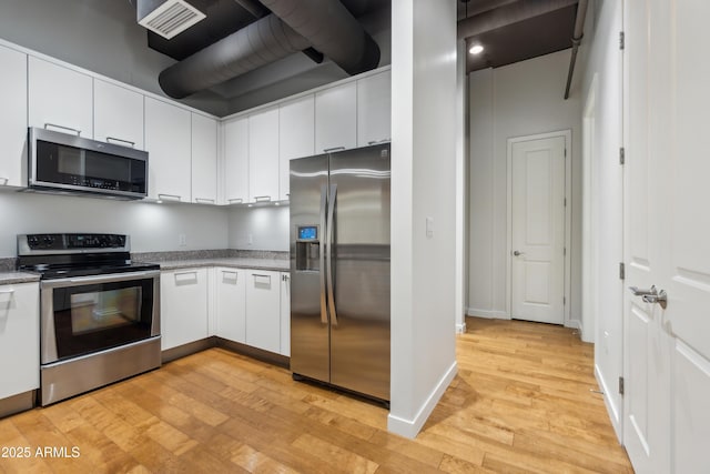 kitchen featuring appliances with stainless steel finishes, light wood-type flooring, and white cabinetry