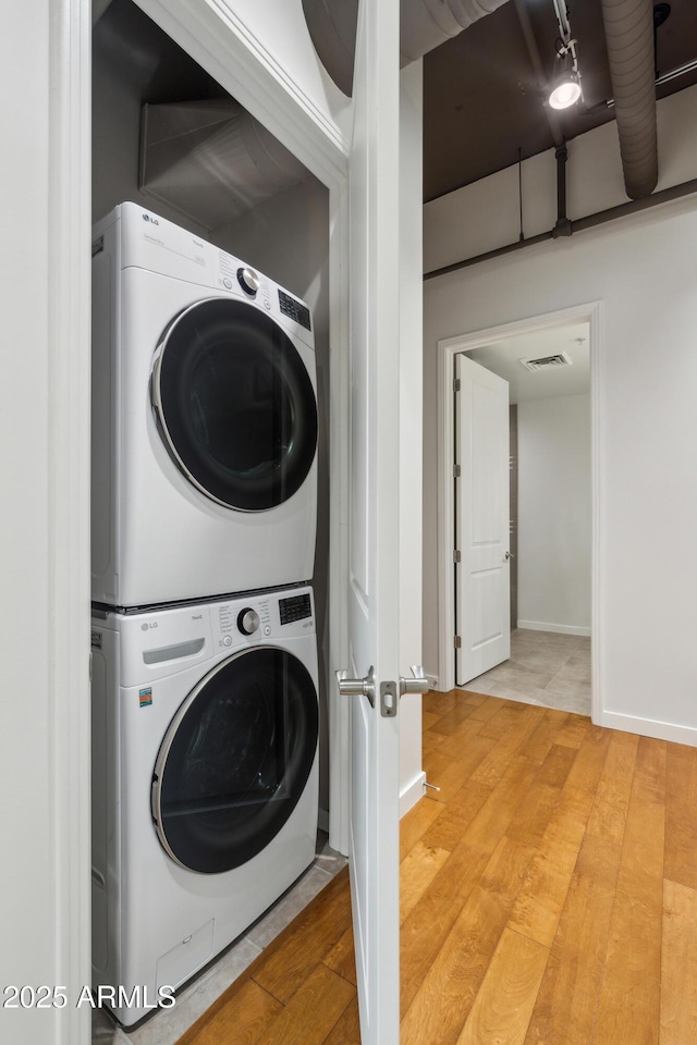 laundry area with hardwood / wood-style flooring and stacked washer / drying machine