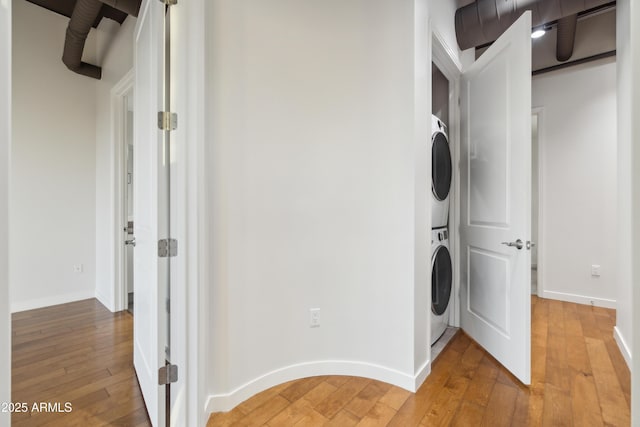 clothes washing area with wood-type flooring and stacked washer / dryer