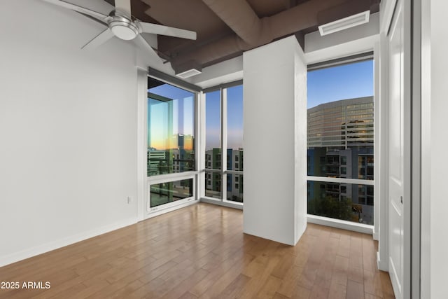 spare room featuring floor to ceiling windows, light hardwood / wood-style floors, and ceiling fan