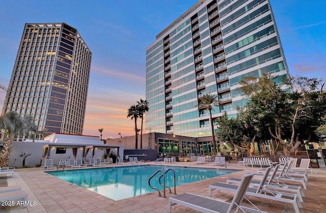 pool at dusk with a patio area