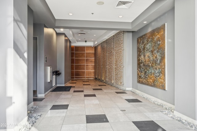 hallway featuring light tile patterned floors and a tray ceiling