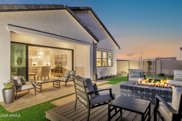 deck at dusk with an outdoor living space with a fire pit and a patio