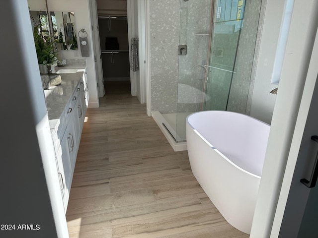 bathroom with wood-type flooring, vanity, and independent shower and bath