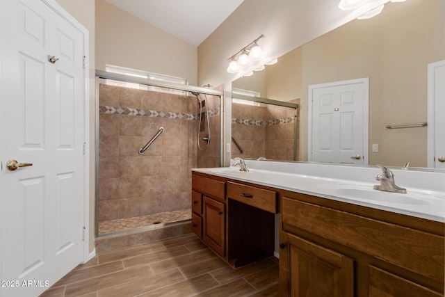 bathroom featuring vanity, vaulted ceiling, and a shower with shower door