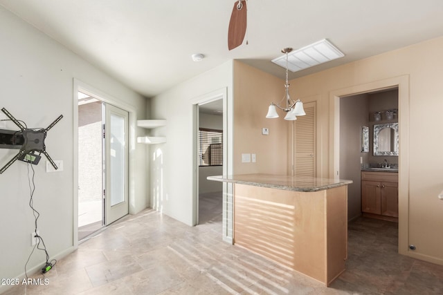 kitchen with sink, pendant lighting, an inviting chandelier, and stone counters