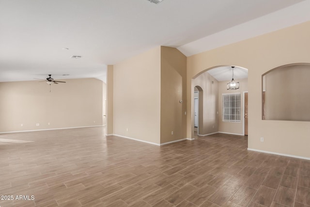 spare room with ceiling fan with notable chandelier, vaulted ceiling, and wood-type flooring