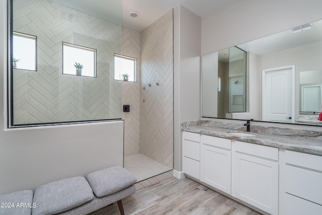 bathroom featuring vanity, hardwood / wood-style floors, and a tile shower