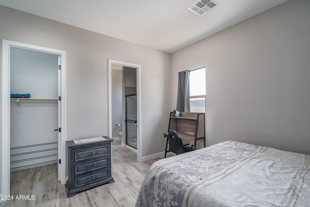 bedroom featuring a spacious closet, light hardwood / wood-style floors, a closet, and ensuite bathroom