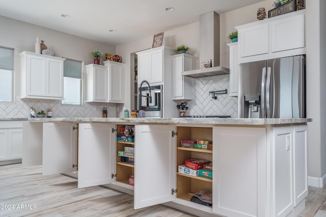 kitchen featuring wall chimney range hood, white cabinets, and appliances with stainless steel finishes